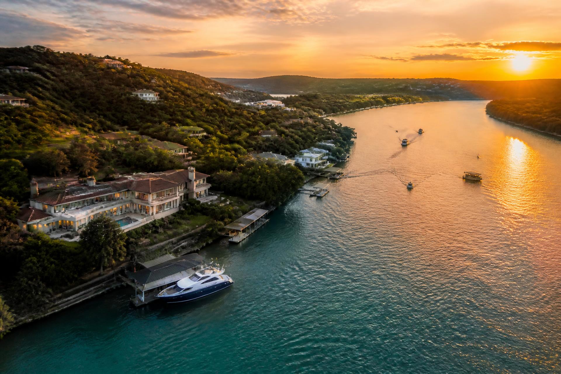 Aerial luxury view of Lake Austin at golden hour with waterfront estates, docks, and boats